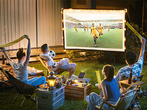 Amigos viendo un partido de fútbol proyectado al aire libre